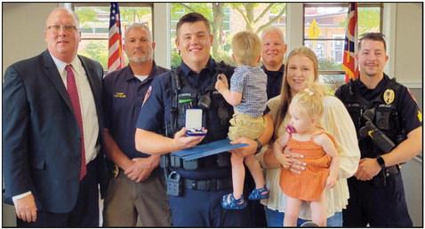 Front row from left are Officer Travis Whitmore, wife Marissa and their twins Maverick and Evelyn; back row, Mayor Neil MacKinnon III, Police Chief Todd Kitzler, Lieutenant Craig Revill and Officer Brandon Lewis.