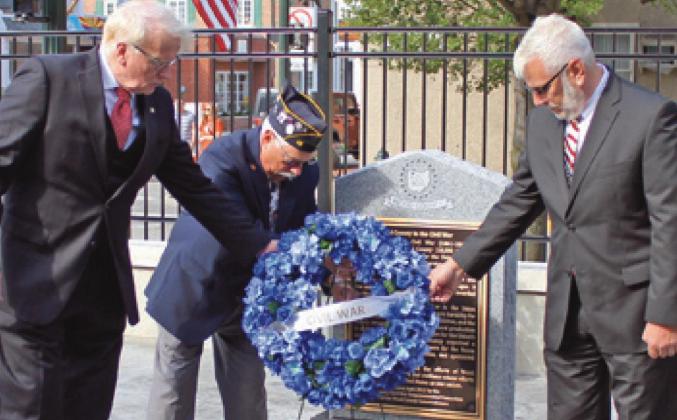 Commissioners Ted Bowlus, left, and Craig LaHote, right, place a wreath at the Civil War memorial.