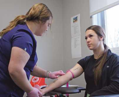 Senior phlebotomy students practice on each other. Hannah Guercio, left, finds a vein before drawing blood from classmate Bella Spellis.