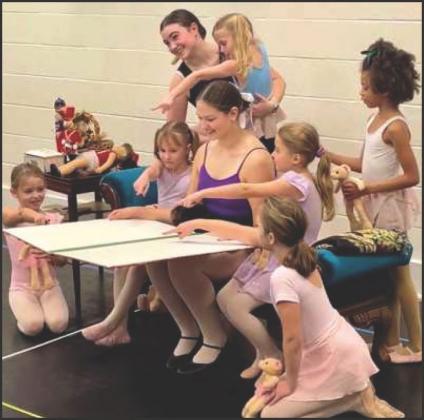 The Nanny, performed by Bryn Rajner, reads a book to young dancers and Clara in the opening scene of the