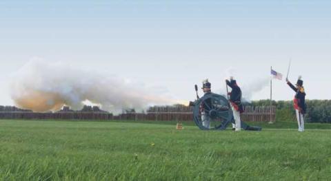 Reenactors fire a cannon.