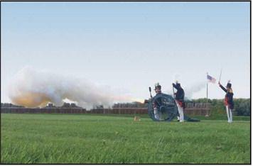 Reenactors fire a cannon.