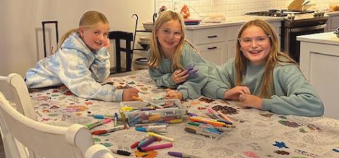 Charlotte, Molly and Abby Murphy unplug by coloring on a Thanksgiving tablecloth.