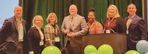 TARTA Chief Customer Experience and Mobility Officer Rick Bailey, center, with the OPTA Collaborative Excellence Award. He was joined on stage by Destination Toledo President and CEO Lance Woodworth, TARTA CEO Laura Koprowski, and TARTA Trustees Mary Morrison, Kendra Smith and Brittany Ford.