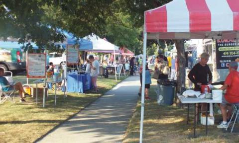 Patrons walk down Dixie Highway as vendors sell fresh produce, food and Rossford themed merchandise.