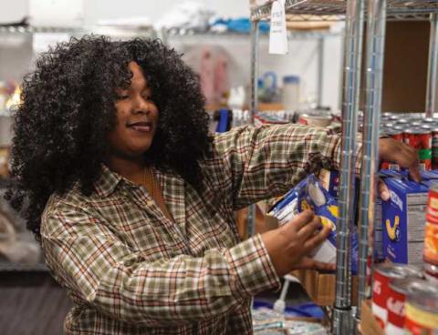Owens student worker Tamia Hayes stocks the shelves of the Harvest Food Pantry. Photo used with permission from Owens Community College.