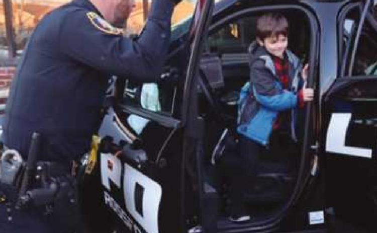 Perrysburg Township Sergeant Dustin Glass helps a child explore one of the police cruisers.