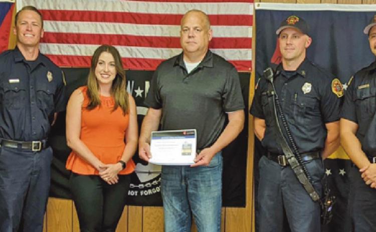 Elizabeth Lewis, center, presents Fire Chief Tom Brice with the AHA award.