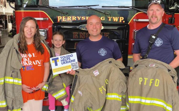 Alona Matchenko, president, Toledo Helps Ukraine; her daughter, Jasmine, and Perrysburg Township Firefighter/Paramedics Mike Thompson and Branden Abke, show some of decommissioned turnout gear donated by the Perrysburg Township Fire Department to be shipped to Ukraine by THU.