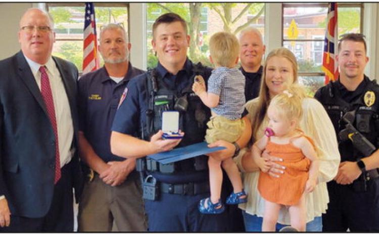 Front row from left are Officer Travis Whitmore, wife Marissa and their twins Maverick and Evelyn; back row, Mayor Neil MacKinnon III, Police Chief Todd Kitzler, Lieutenant Craig Revill and Officer Brandon Lewis.