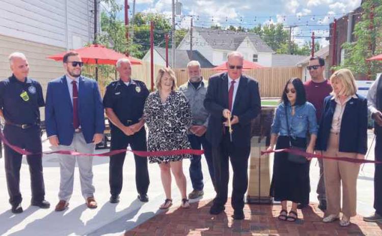 Above, City of Rossford and TARTA representatives cut the ribbon on the completed park. Below right, the pocket park features picnic tables with umbrellas, turf, a water feature and string lighting.