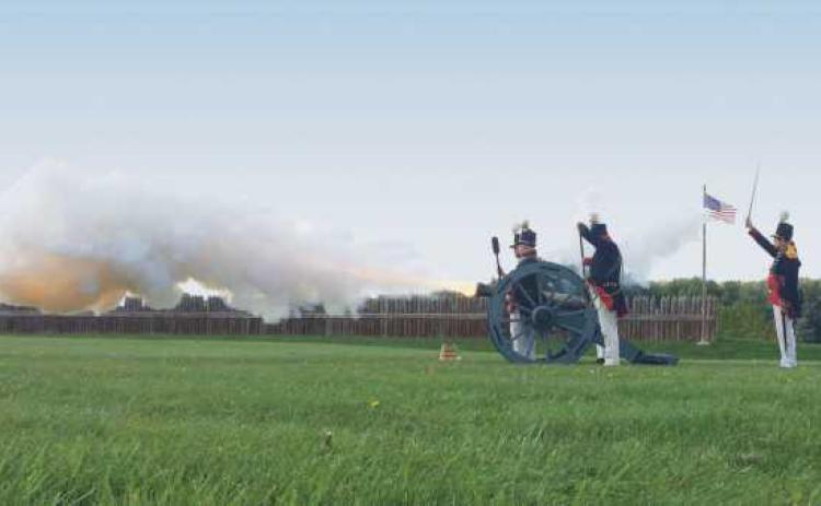 Reenactors fire a cannon.