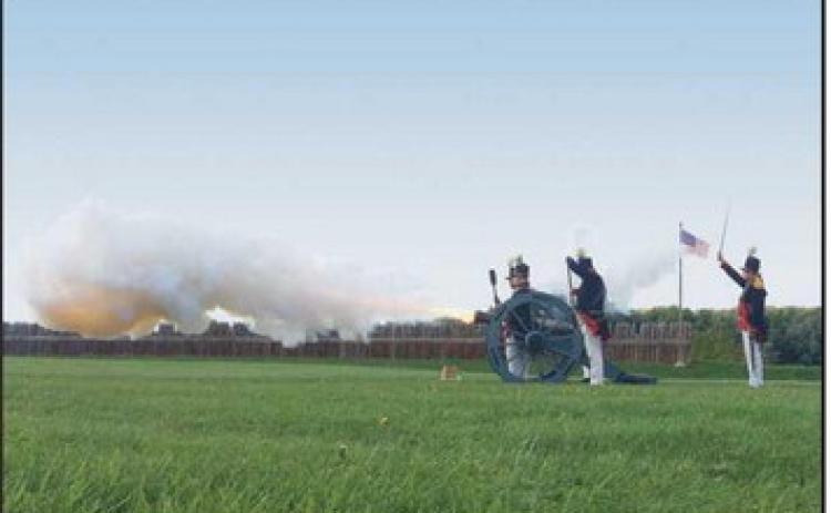 Reenactors fire a cannon.