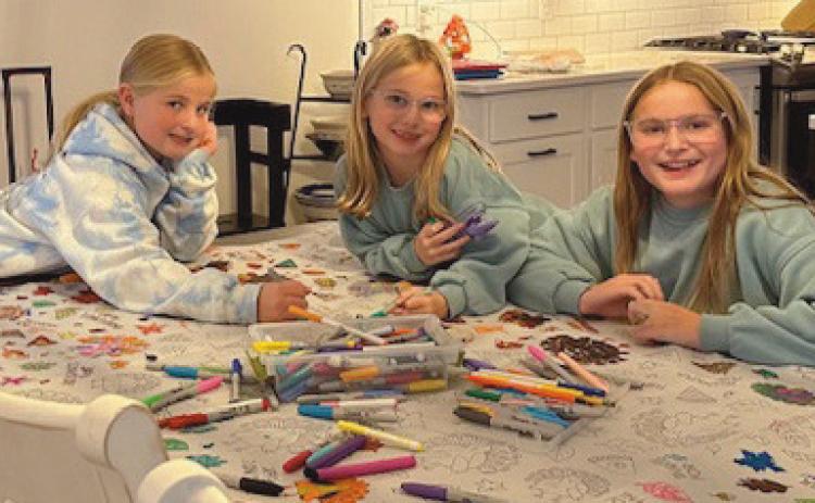 Charlotte, Molly and Abby Murphy unplug by coloring on a Thanksgiving tablecloth.