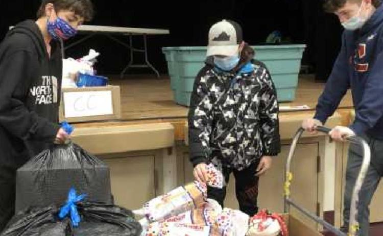 Students volunteer to assist with assembling the boxes of food and gifts for the families in need.