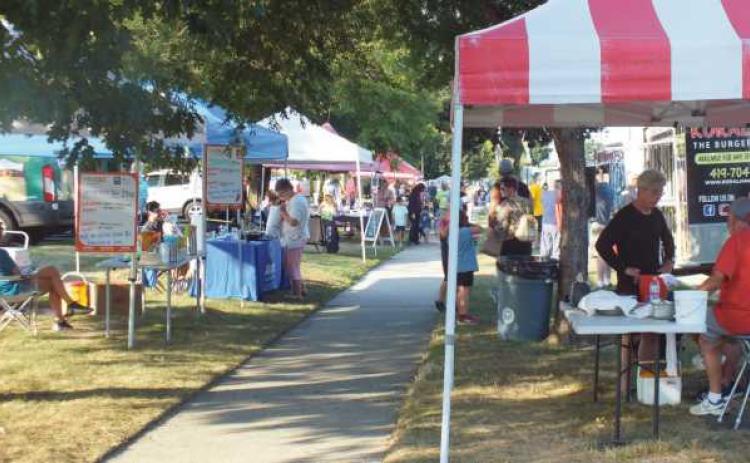 Patrons walk down Dixie Highway as vendors sell fresh produce, food and Rossford themed merchandise.