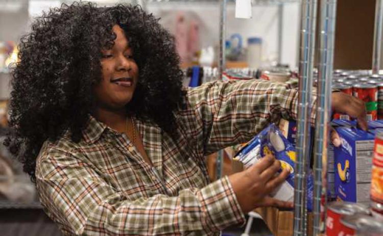 Owens student worker Tamia Hayes stocks the shelves of the Harvest Food Pantry. Photo used with permission from Owens Community College.