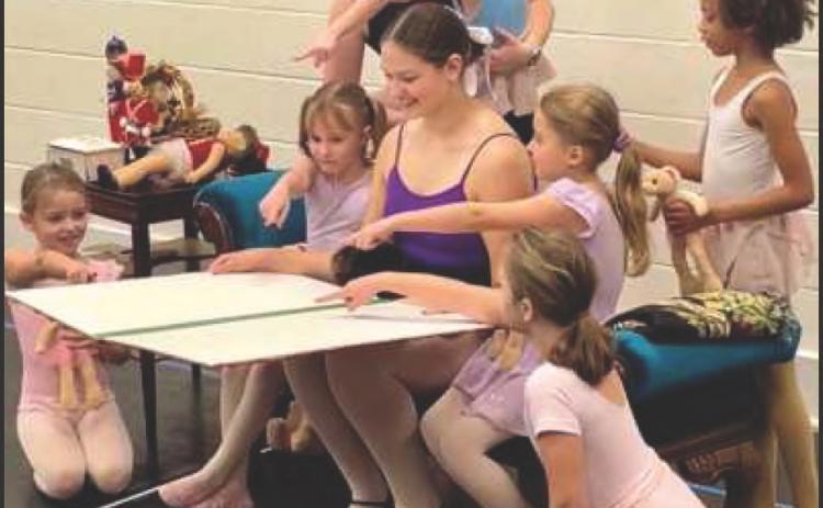 The Nanny, performed by Bryn Rajner, reads a book to young dancers and Clara in the opening scene of the